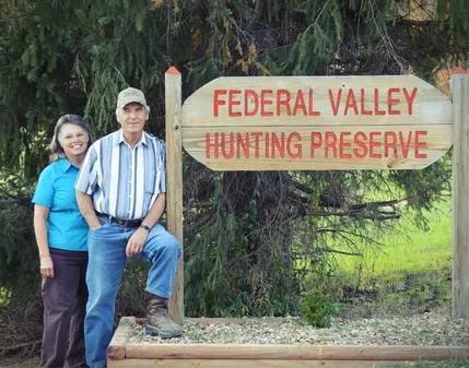 Gene and Roseanna Hines standing beside the Federal Valley Hunting Preserve sign